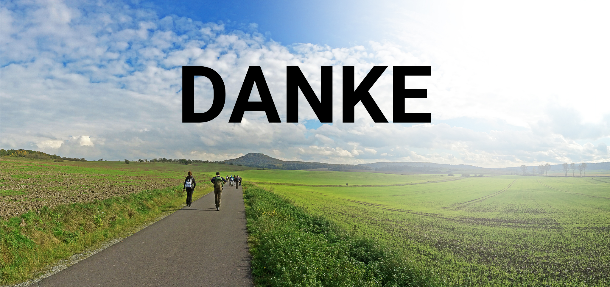 Menschen, die auf einem Weg im grünen Feld, der vom Betrachter zum Horizont führt gehen.